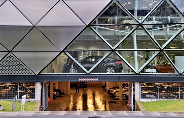 Modern multi-story building featuring cars on display behind large windows.