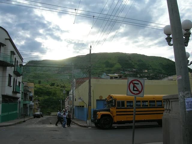 Yellow school bus on a street in Tegucigalpa, Honduras, with a mountain in the background.