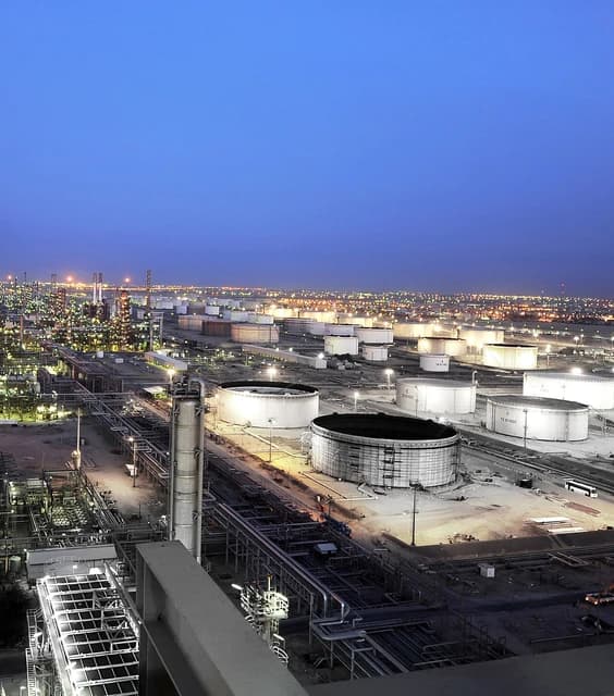 An aerial view of the illuminated Al-Ahmadi oil refinery in Kuwait at dusk.