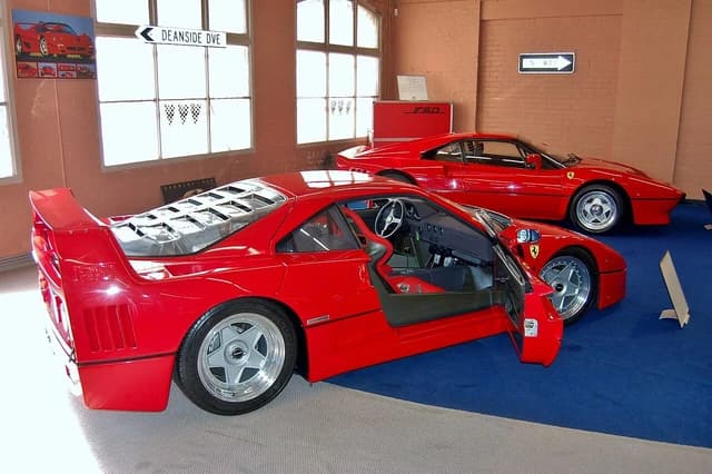 Two red Ferrari sports cars, one with an open door, displayed in a collection.