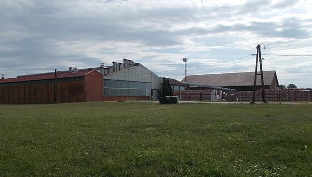 Exterior view of Tondach tile factory buildings and stacked products under a cloudy sky.