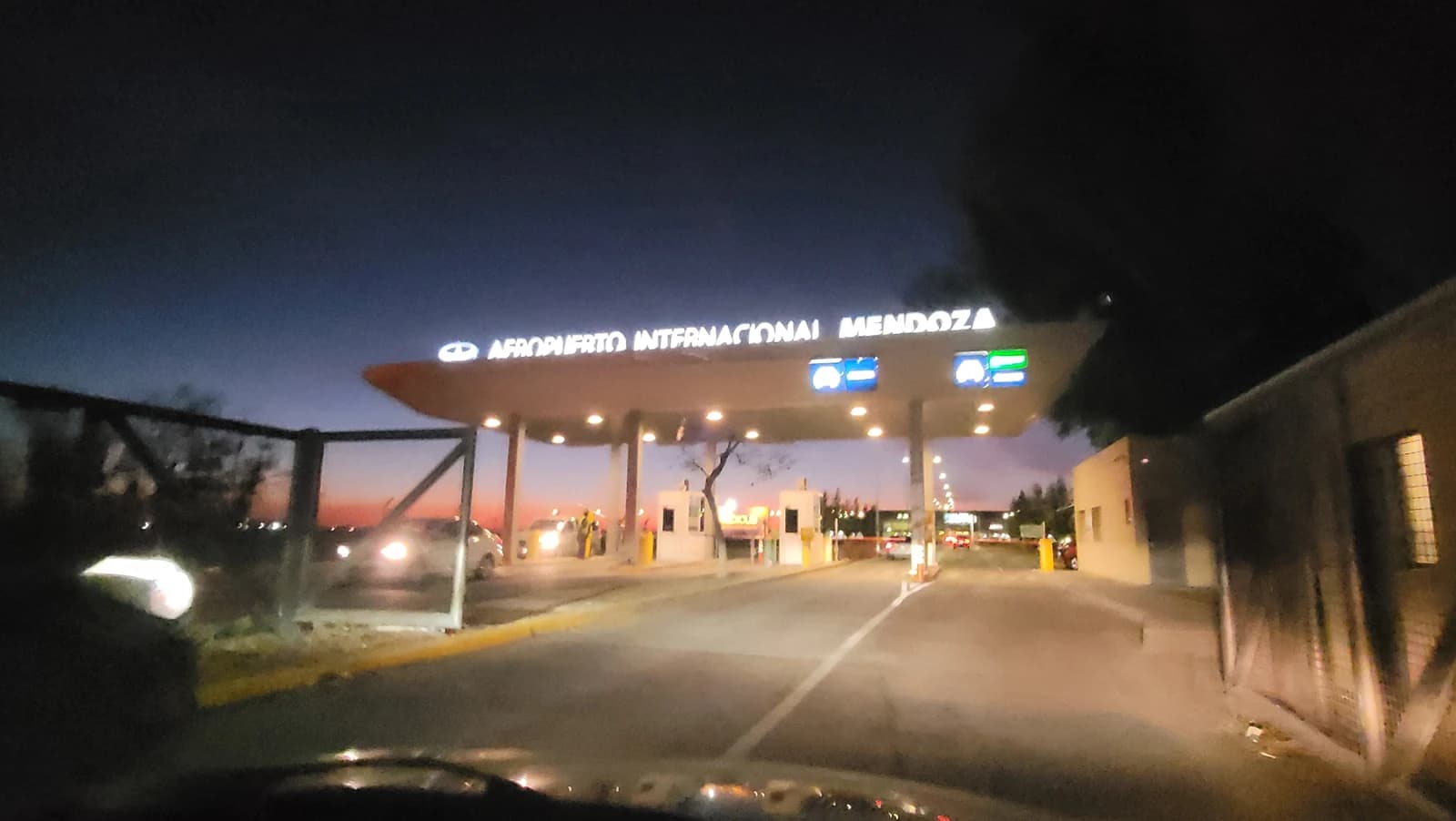 Entrance sign for Aeropuerto Internacional Mendoza at night with vehicle lights.