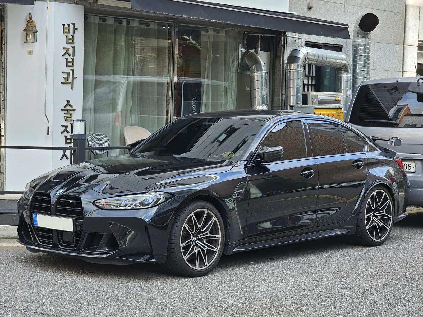 Black BMW G80 M3 Competition M xDrive parked on a city street.