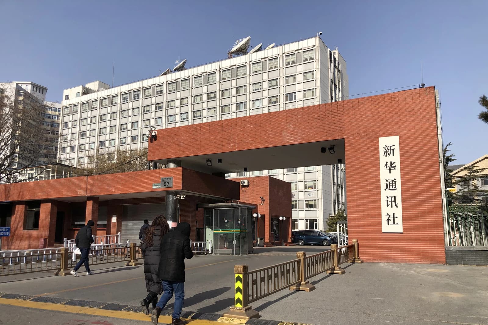 Pedestrians walk past the main gate of Xinhua News Agency headquarters building.