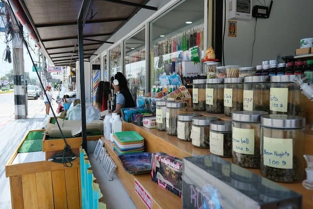 Sales attendant chatting with customers at a street-side shop.