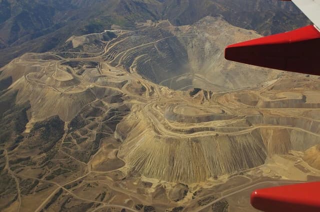 Aerial view showing a vast open-pit copper mine with terraced slopes and access roads.