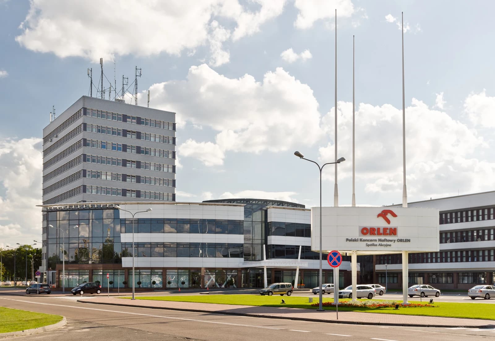 Exterior view of the Orlen office building in Płock, Poland, under a partly cloudy sky.