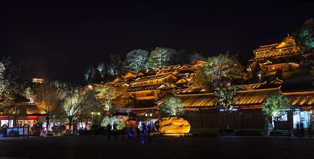 Traditional buildings with illuminated rooftops at night in Lijiang Old Town, China.