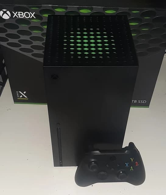Xbox Series X console and a black wireless controller on a white surface.