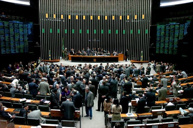 Brazilian Chamber of Deputies interior with numerous representatives and staff during a legislative session.