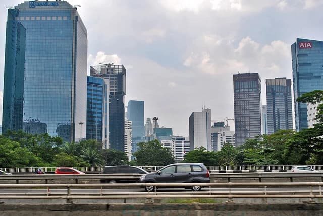 Skyscrapers towering over a busy elevated highway with moving cars in Jakarta.