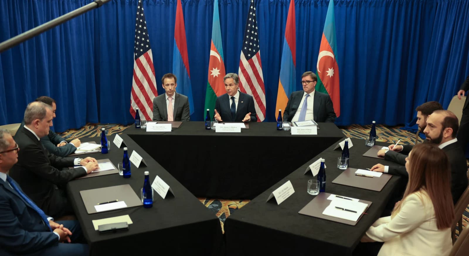 Secretary Antony Blinken gestures while seated at a table with Armenian and Azerbaijani Foreign Ministers.