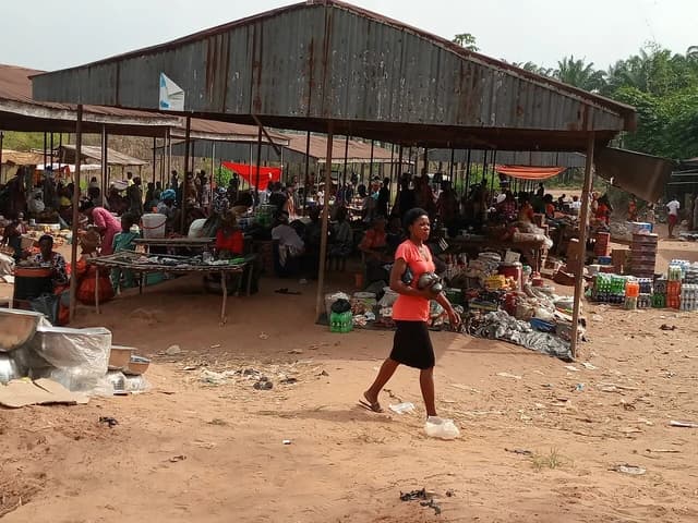 A woman carrying items walks through a busy market in rural Nigeria.