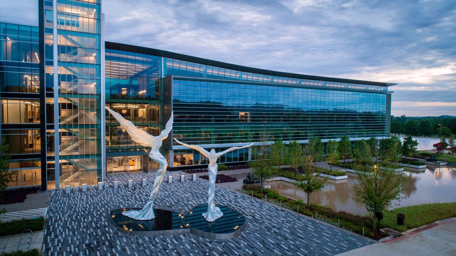 Bank OZK headquarters building with modern glass facade and outdoor sculptures.