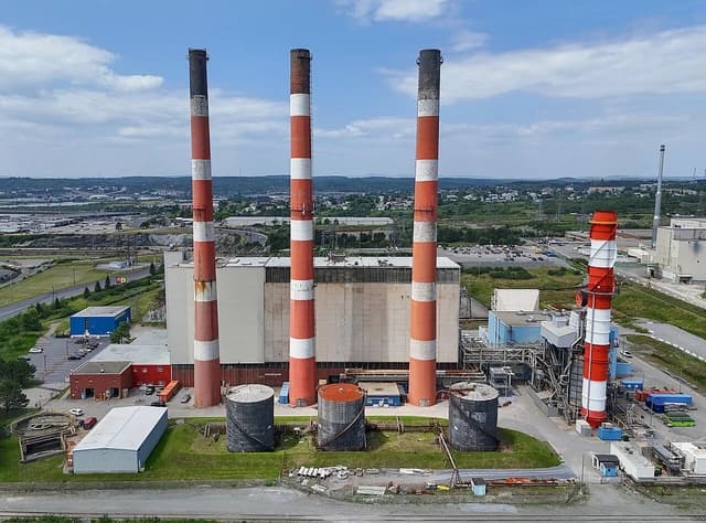 Aerial view of Bayside Generating Station with several tall, red and white striped smokestacks.