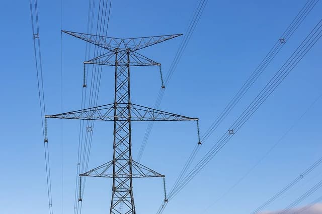 Power transmission lines and a large pylon under a clear blue sky.
