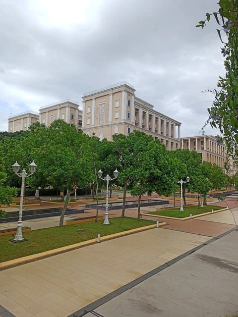 Infosys campus in Mysuru, Karnataka, featuring buildings, trees, and pathways under a cloudy sky.