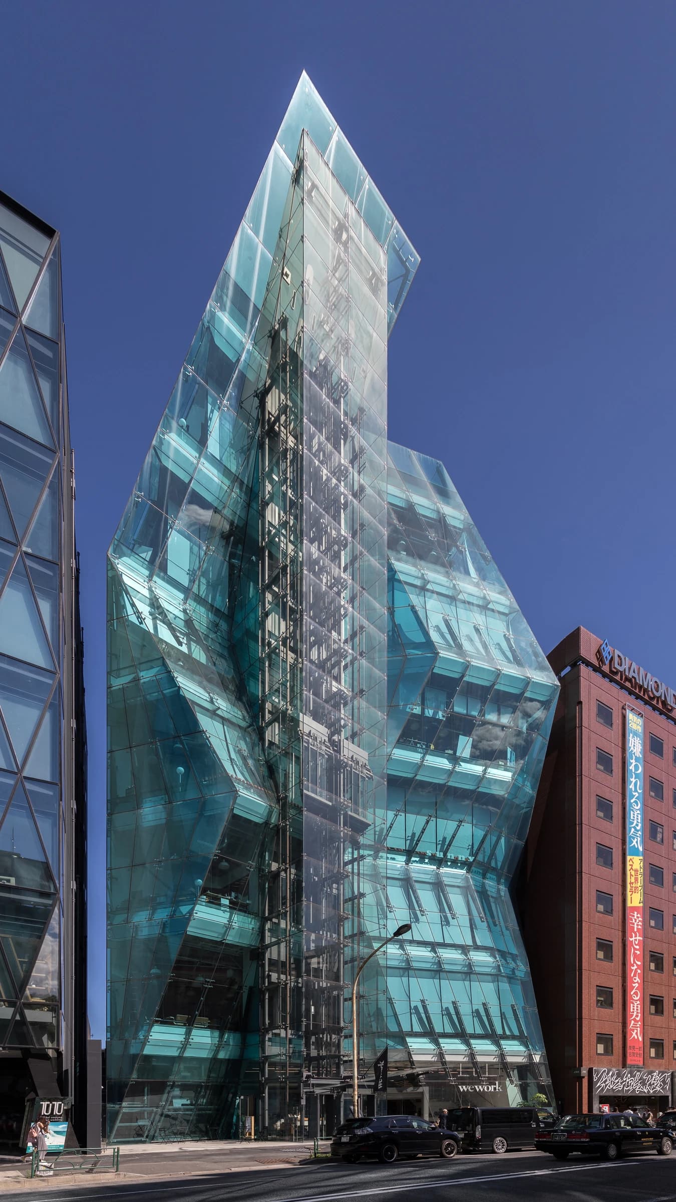 The Iceberg, a modern glass building in Shibuya, Tokyo, under a clear sky.