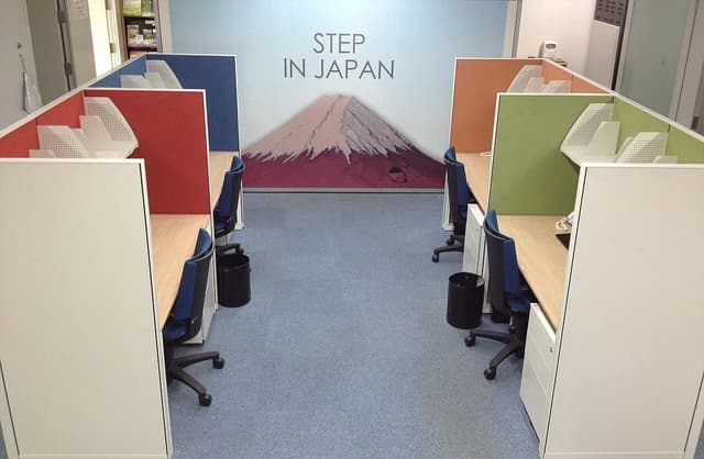 An empty office space with multiple cubicles, chairs, and a mural of Mount Fuji.