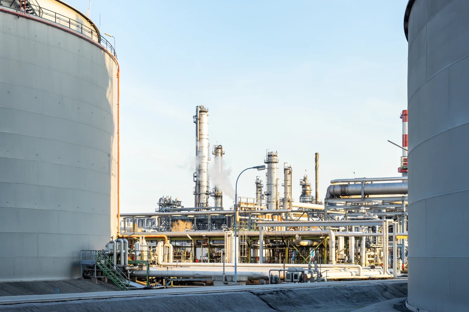 An industrial oil refinery complex with multiple towers, pipes, and large storage tanks.