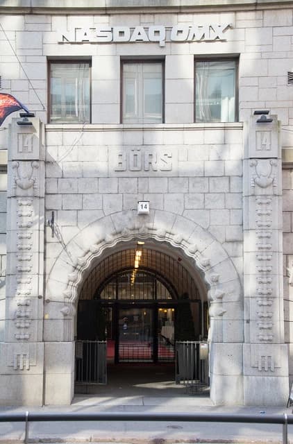 Exterior view of a stone building with NASDAQ OMX signage above an arched entrance.