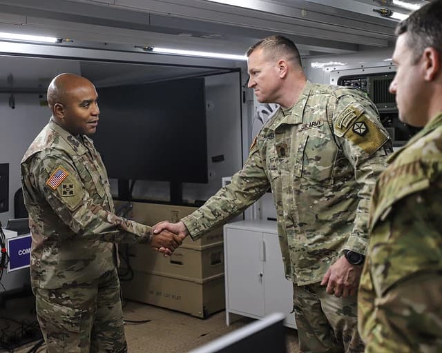 Military leaders shaking hands inside V Corps Forward Headquarters.