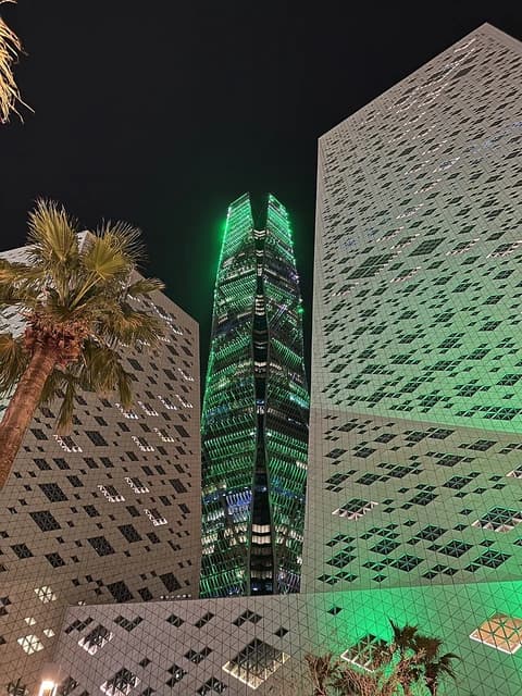 The PIF Tower, a prominent skyscraper, lit up in green against a night sky.