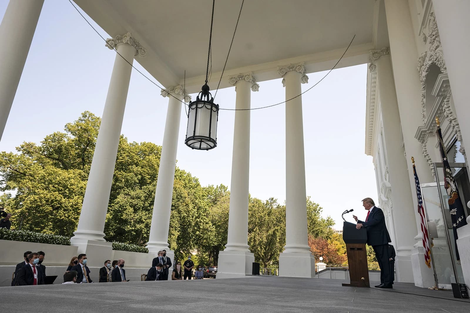 President Donald Trump speaking at a podium outdoors at the White House.