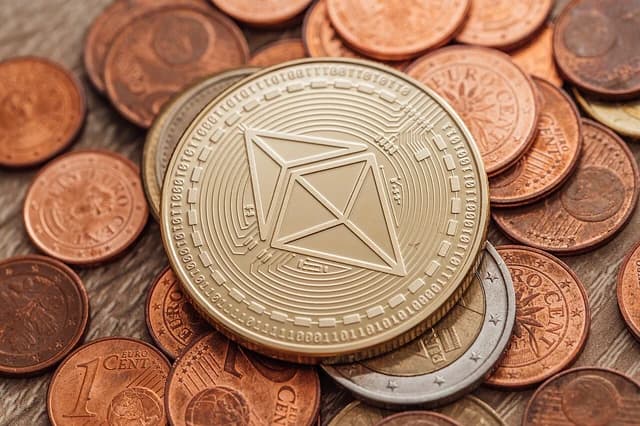 Close-up of a golden physical Ethereum coin resting on various copper and silver Euro coins.