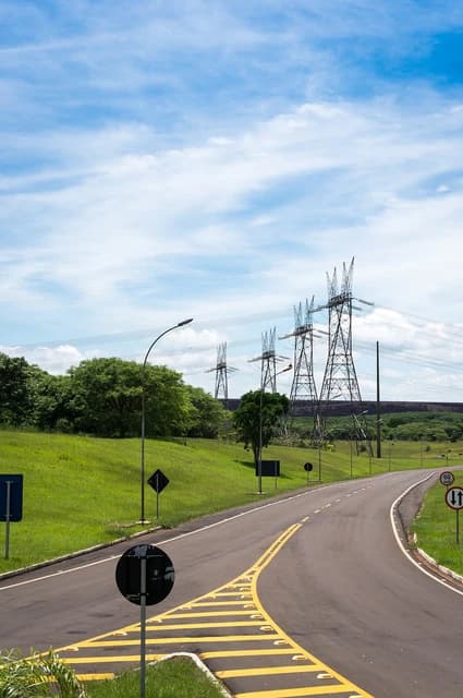 Transmission towers and a road with yellow markings near the Itaipu Binacional Dam.
