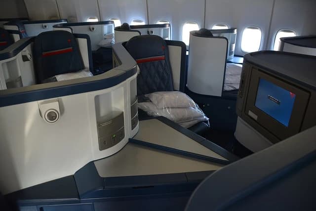Empty business class seats inside a Delta Air Lines airplane cabin.