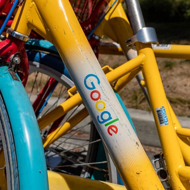 Close-up of Google logo on the frame of a yellow and blue bicycle.