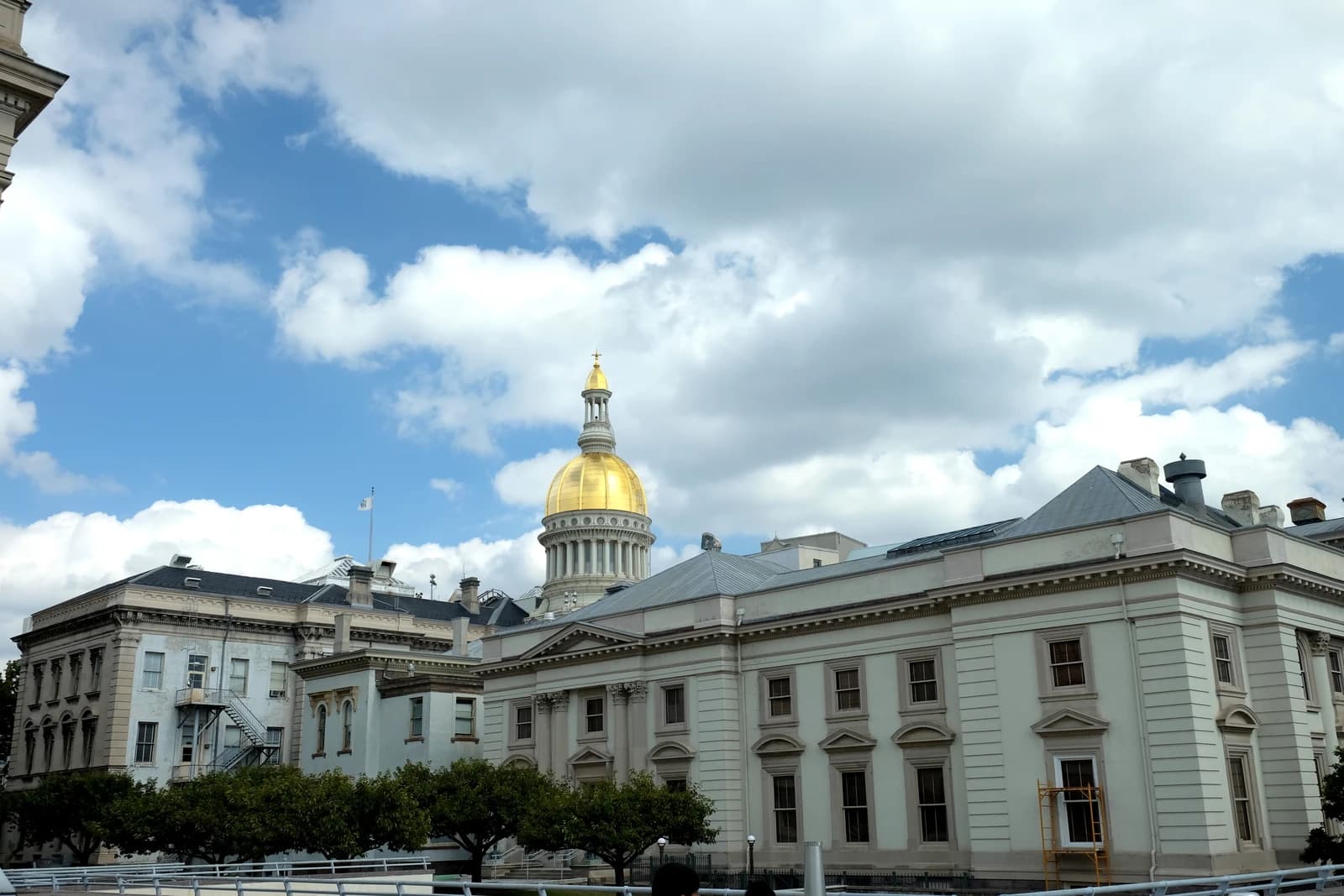 New Jersey State House building with a prominent golden dome against a blue sky.