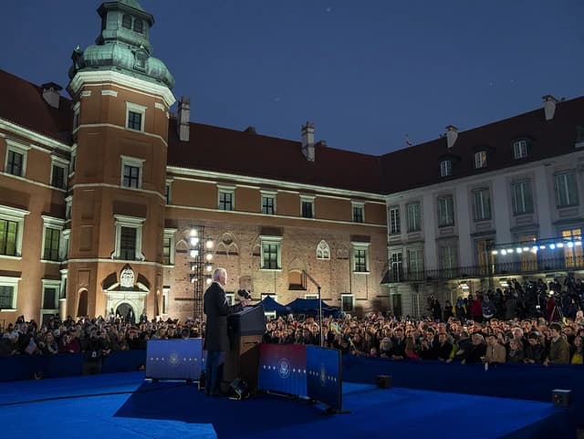 President Joe Biden delivers remarks at a podium to a crowd outside the Royal Castle in Warsaw.