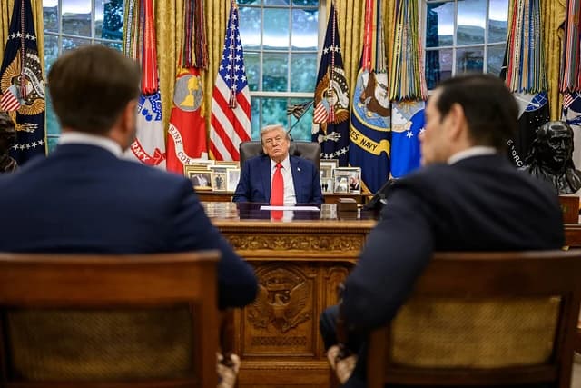 Donald Trump, former President of the United States, seated at his desk in the Oval Office.