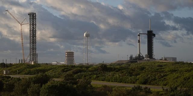 SpaceX Falcon 9 rocket and Crew Dragon spacecraft on launchpad with crew access arm.