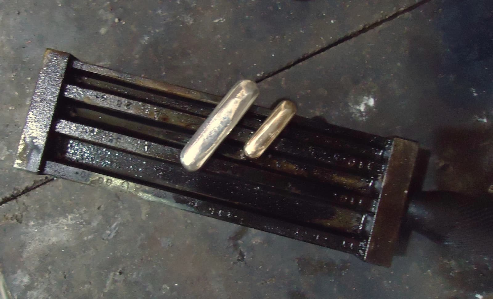 One silver ingot and one gold ingot lying next to each other.