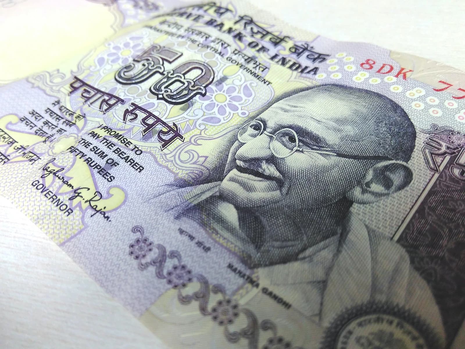 Close-up of a purple Indian 50-rupees banknote with Mahatma Gandhi's portrait on the right.