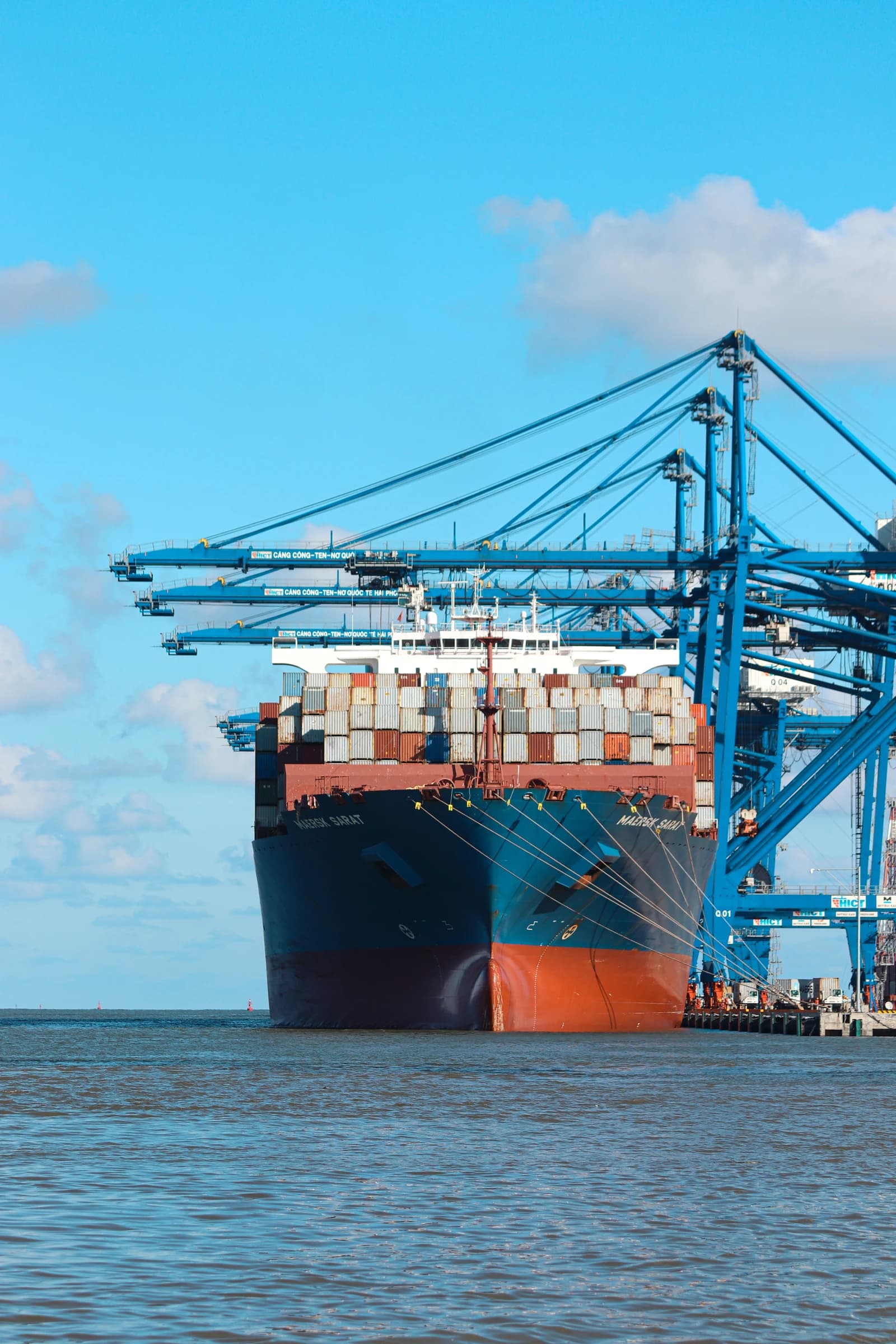Large container ship docked at Hai Phong International Container Terminal under blue sky.