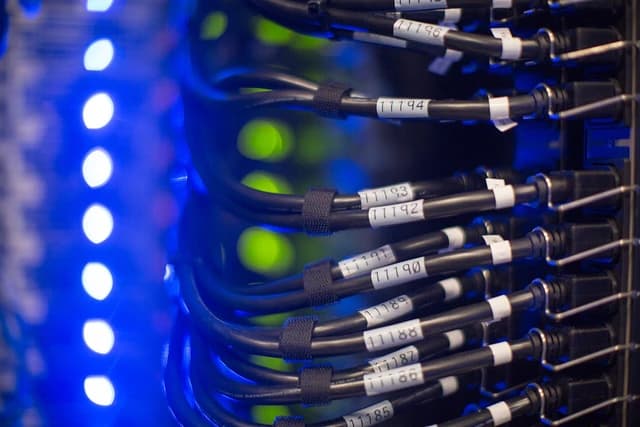Close-up of server rack with numerous black cables connected to equipment.
