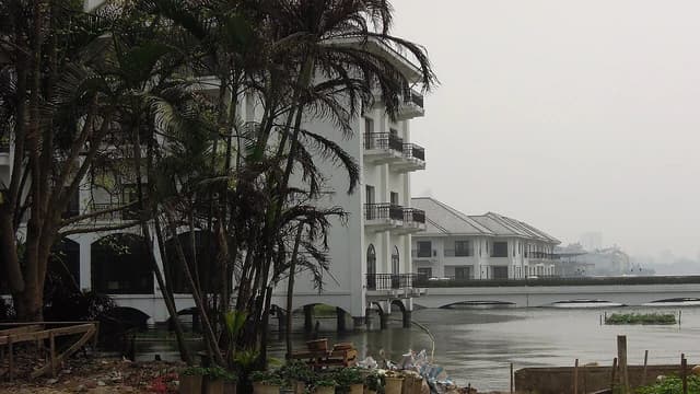 Luxury buildings along West Lake, Hanoi, Vietnam, with a bridge in the distance.