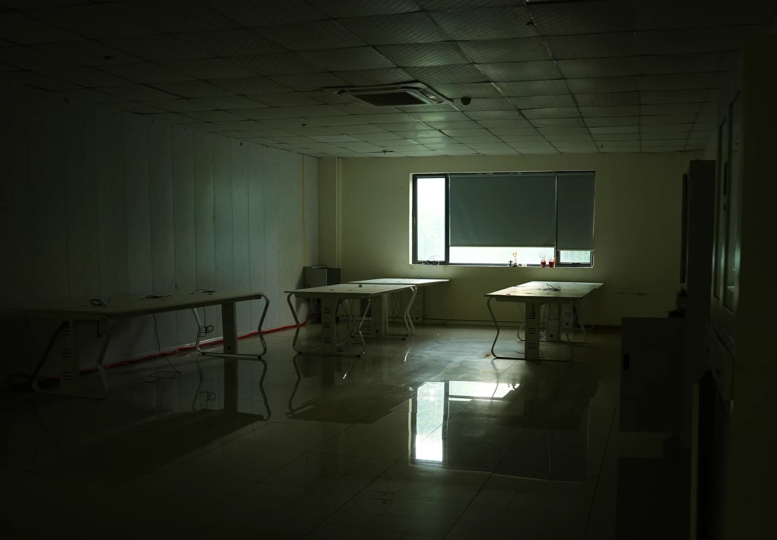 Empty tables and reflections of light in a room, likely from a raided scam operation.