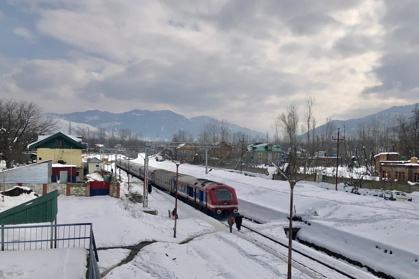 An Indian Railways train arriving at Hiller station in Jammu and Kashmir, covered in snow.