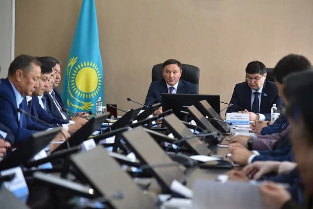 Kazakhstani officials Marjyqpaev and Takiev attend a government meeting with other participants.