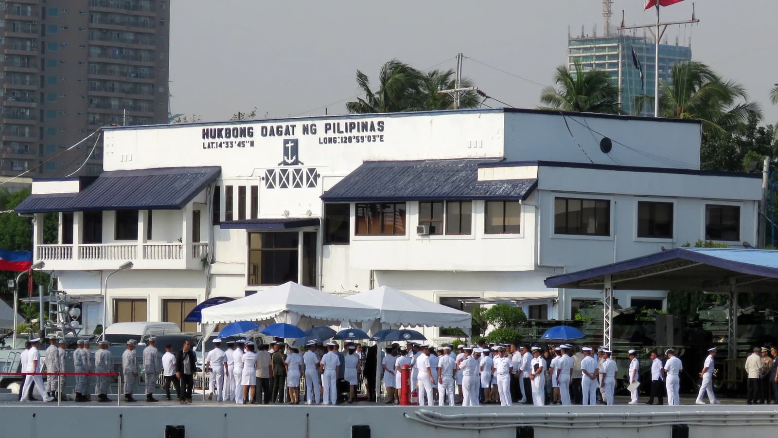 Philippine Navy Headquarters building with a large gathering of uniformed personnel on the waterfront.