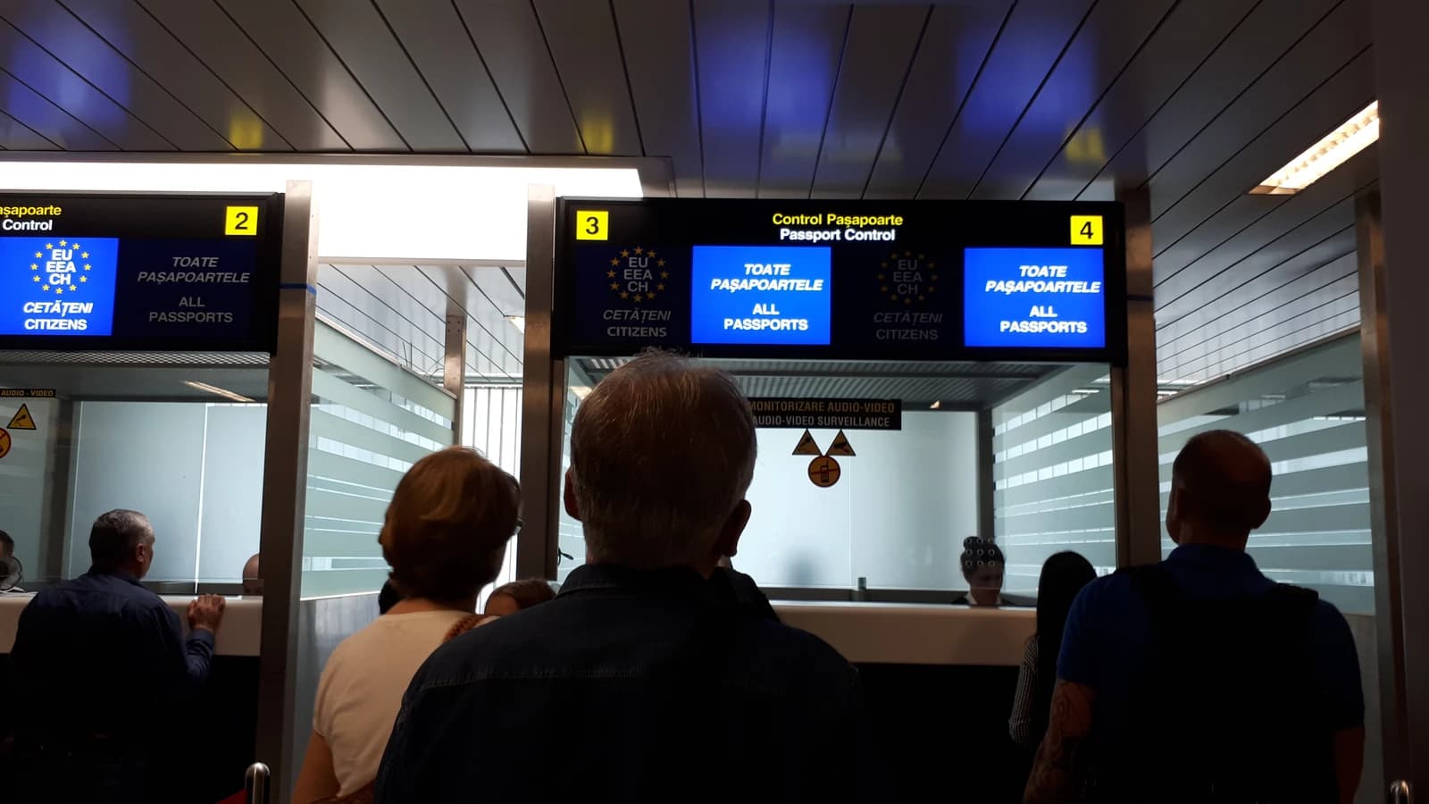 People queuing at passport control booths at Henri Coandă Airport.