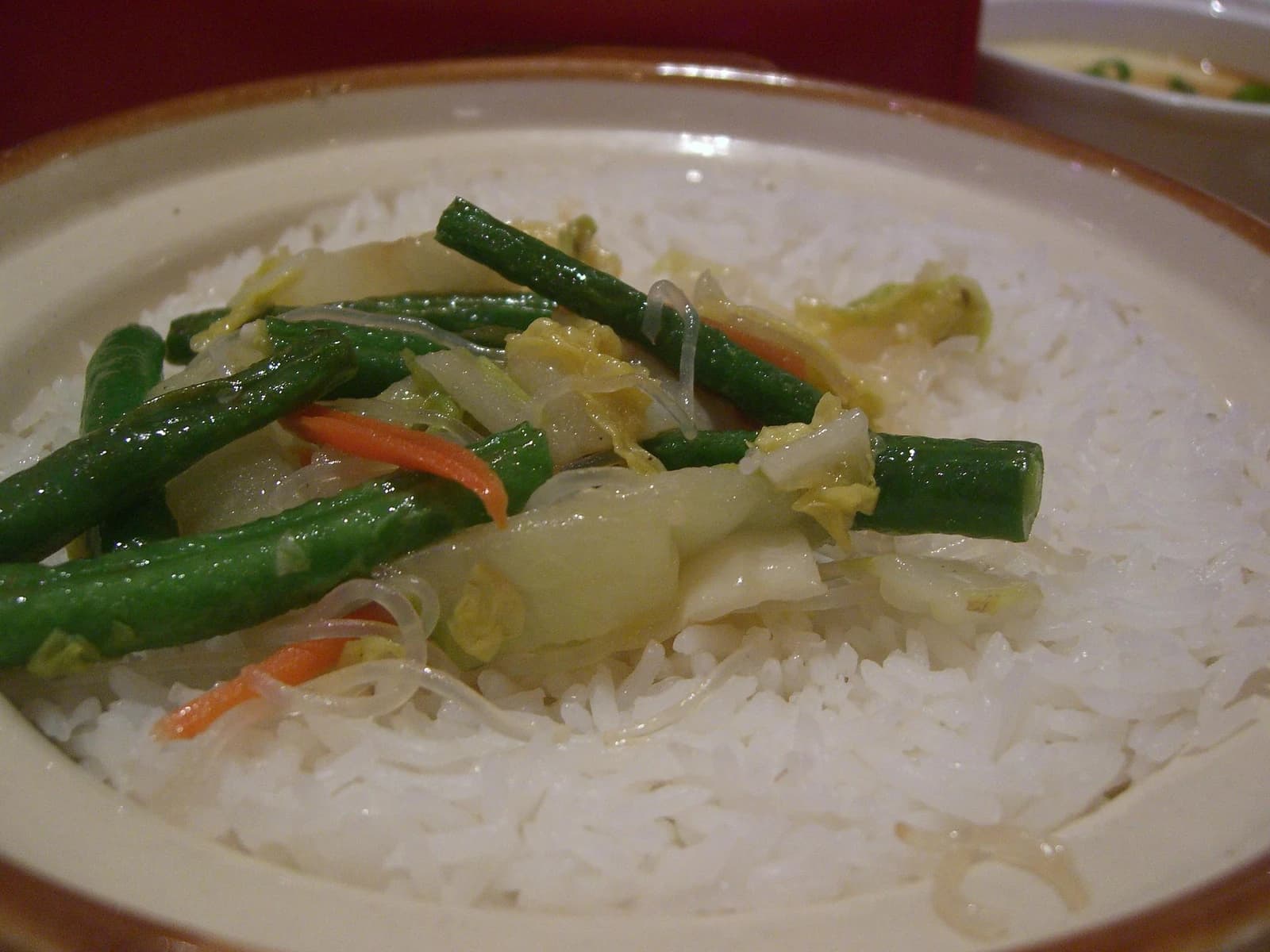 Plate of white rice with green beans, cabbage, and shredded carrots.