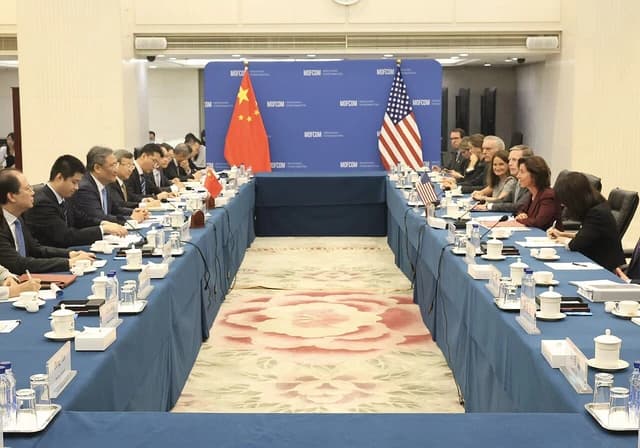 Gina Raimondo and Wang Wentao seated at a long conference table with flags.