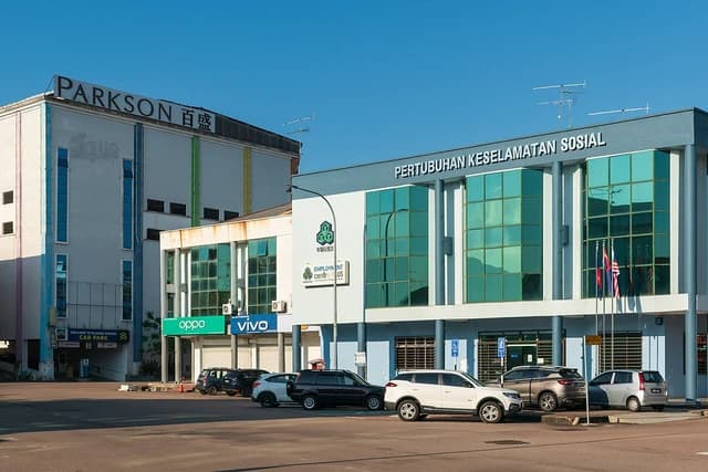 Exterior of Social Security Organization building in Kluang with parked cars.
