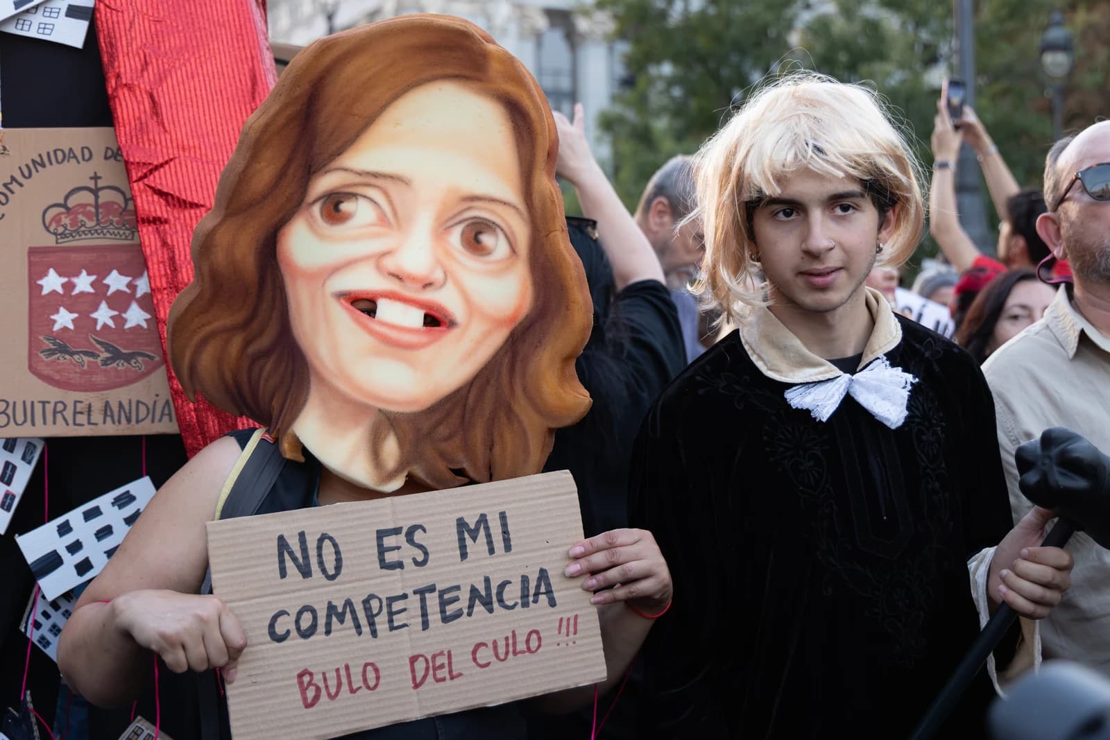 Protesters in Madrid holding signs and wearing costumes at a housing rights demonstration.